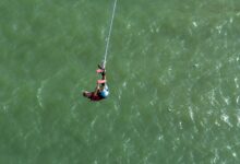 Person bungee jumping from high platform with scenic mountain landscape in background