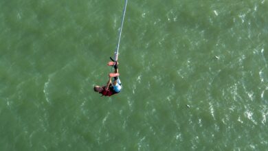 Person bungee jumping from high platform with scenic mountain landscape in background