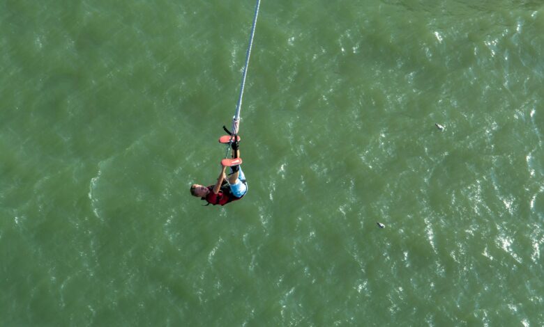 Person bungee jumping from high platform with scenic mountain landscape in background