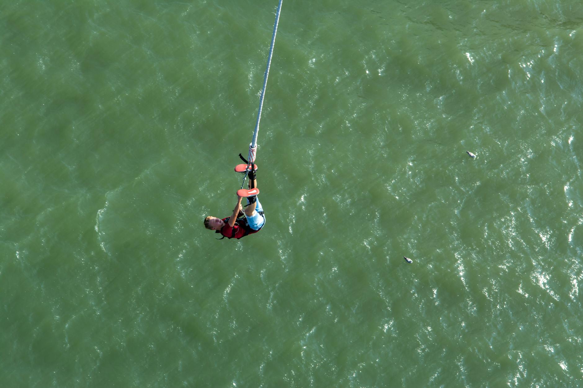Person bungee jumping from high platform with scenic mountain landscape in background