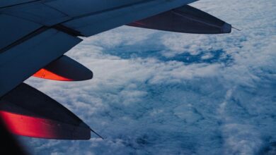 View from airplane window showing wing and clouds during flight over Europe