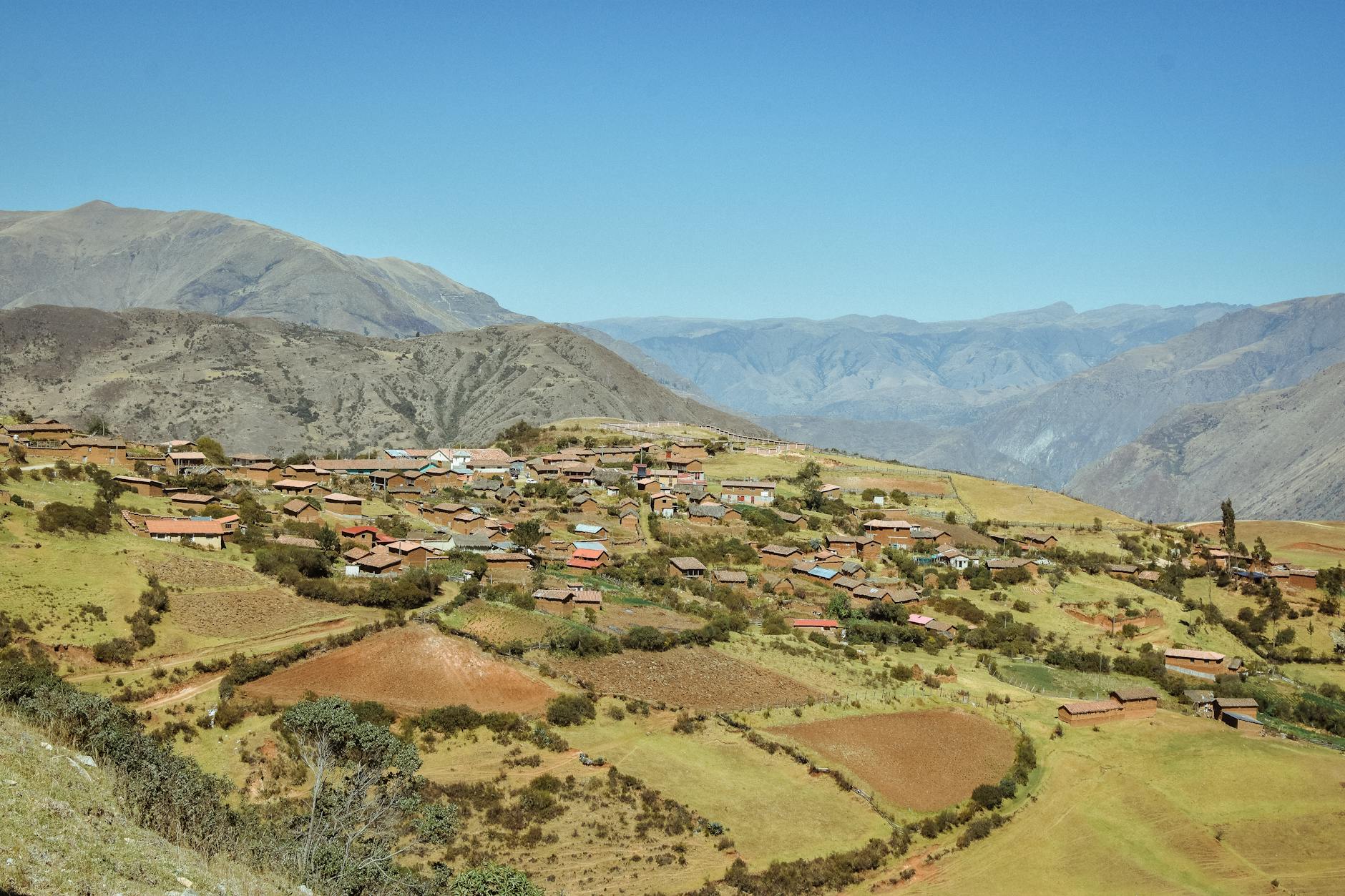 Traditional stone houses built into mountainside with terraced gardens in Morocco's High Atlas region