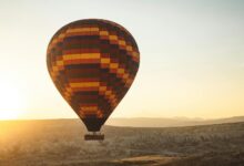 Colorful hot air balloon floating over African savanna landscape at sunrise
