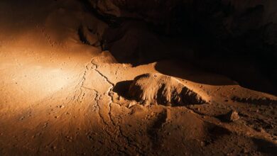 Underground limestone cave chamber with natural rock formations and ambient lighting