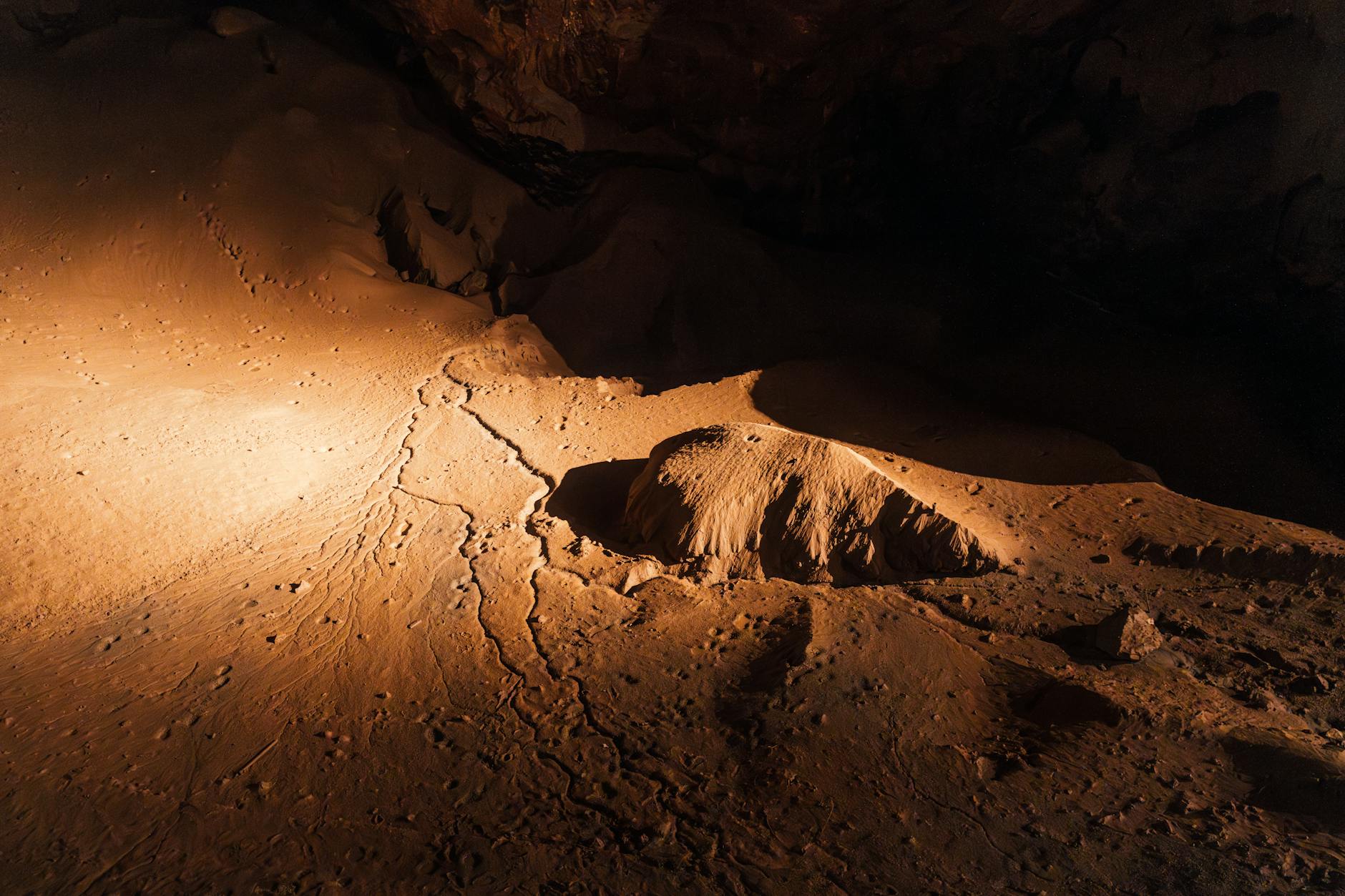 Underground limestone cave chamber with natural rock formations and ambient lighting