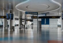 Modern airport lounge interior with comfortable seating, large windows, and travelers relaxing