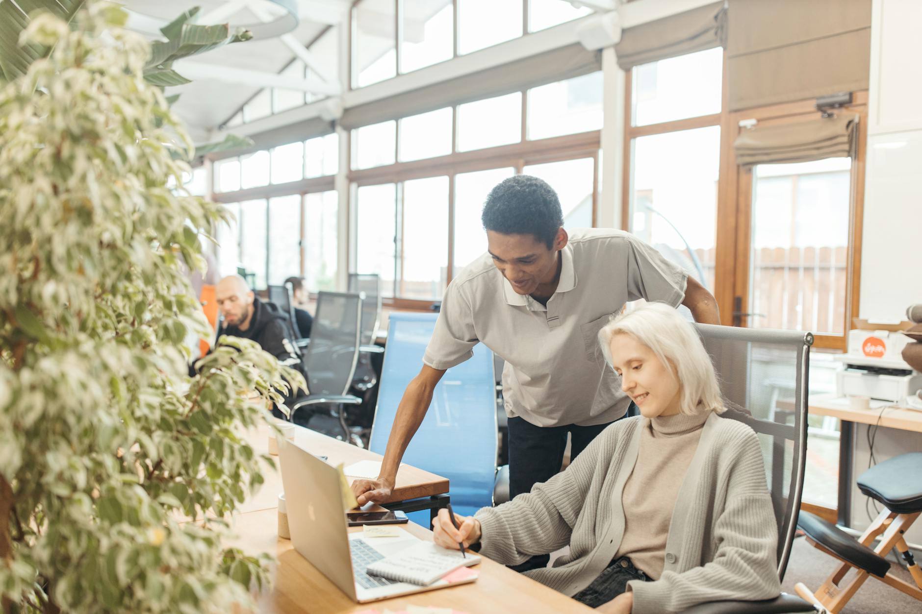 Modern co-working space with laptops and people working at shared tables