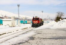 Train traveling through snowy Arctic landscape with snow-covered tracks and winter terrain