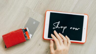 Multiple credit cards fanned out next to a leather wallet on a wooden surface