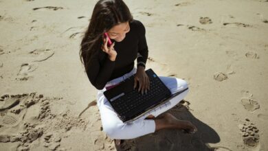 Person working on laptop at beachside cafe table
