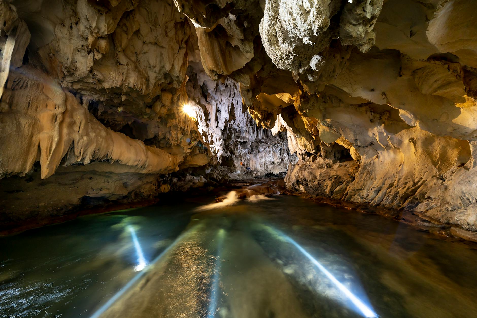 Crystal clear cenote water in underground limestone cave with natural light filtering through opening