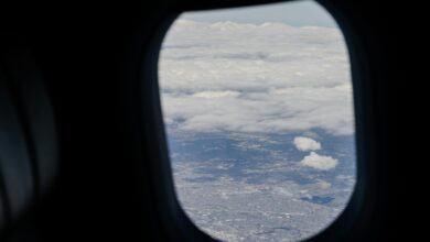 Airplane passenger looking out window at bright sky during flight