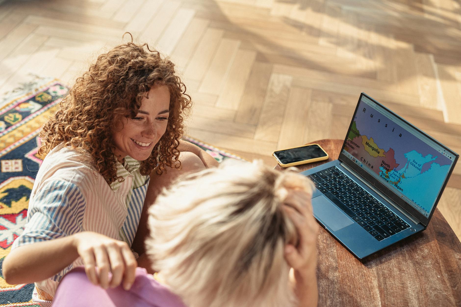Group of friends sitting around table with maps and laptops planning their vacation together