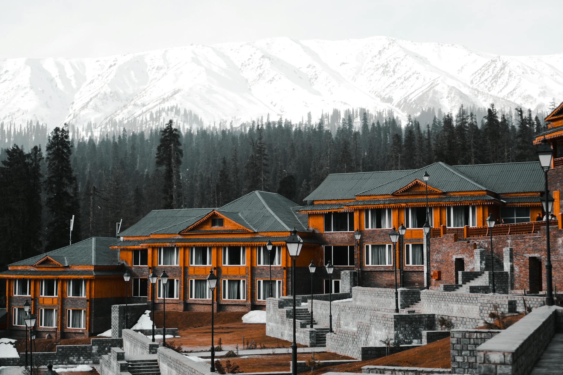 Snow-covered mountain lodge with traditional stone architecture against mountain peaks