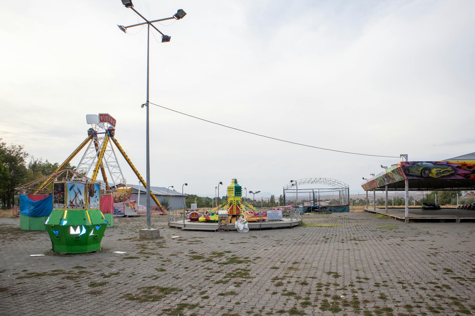 Empty roller coaster tracks overgrown with vegetation against cloudy sky