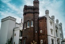 Medieval Gothic castle with pointed arches and stone towers against cloudy sky