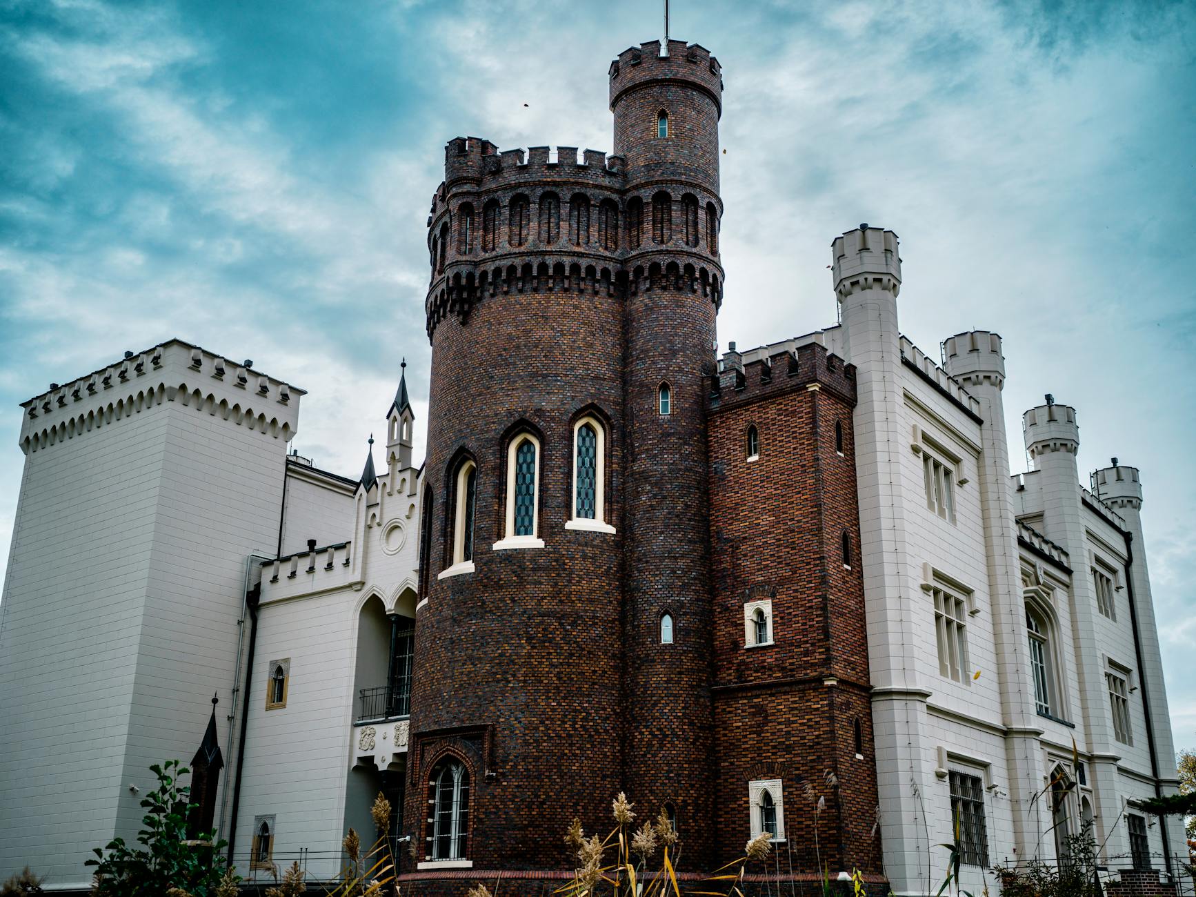 Medieval Gothic castle with pointed arches and stone towers against cloudy sky