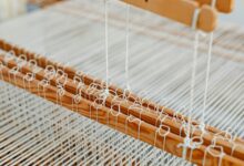 Traditional textile loom with colorful threads being woven by hand in workshop setting
