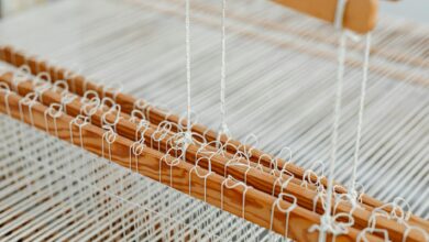 Traditional textile loom with colorful threads being woven by hand in workshop setting