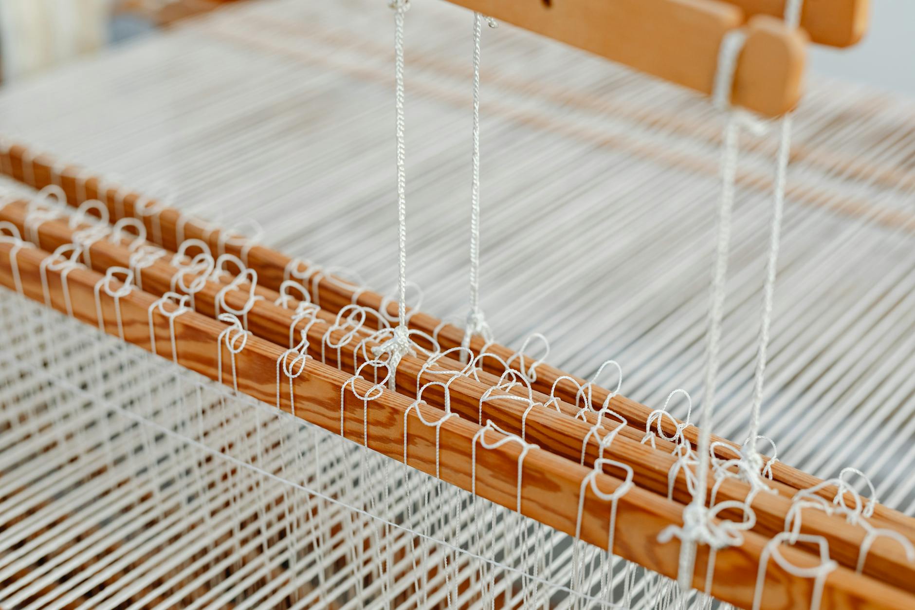 Traditional textile loom with colorful threads being woven by hand in workshop setting