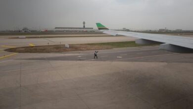 Travelers moving through airport security checkpoint with metal detectors and screening equipment
