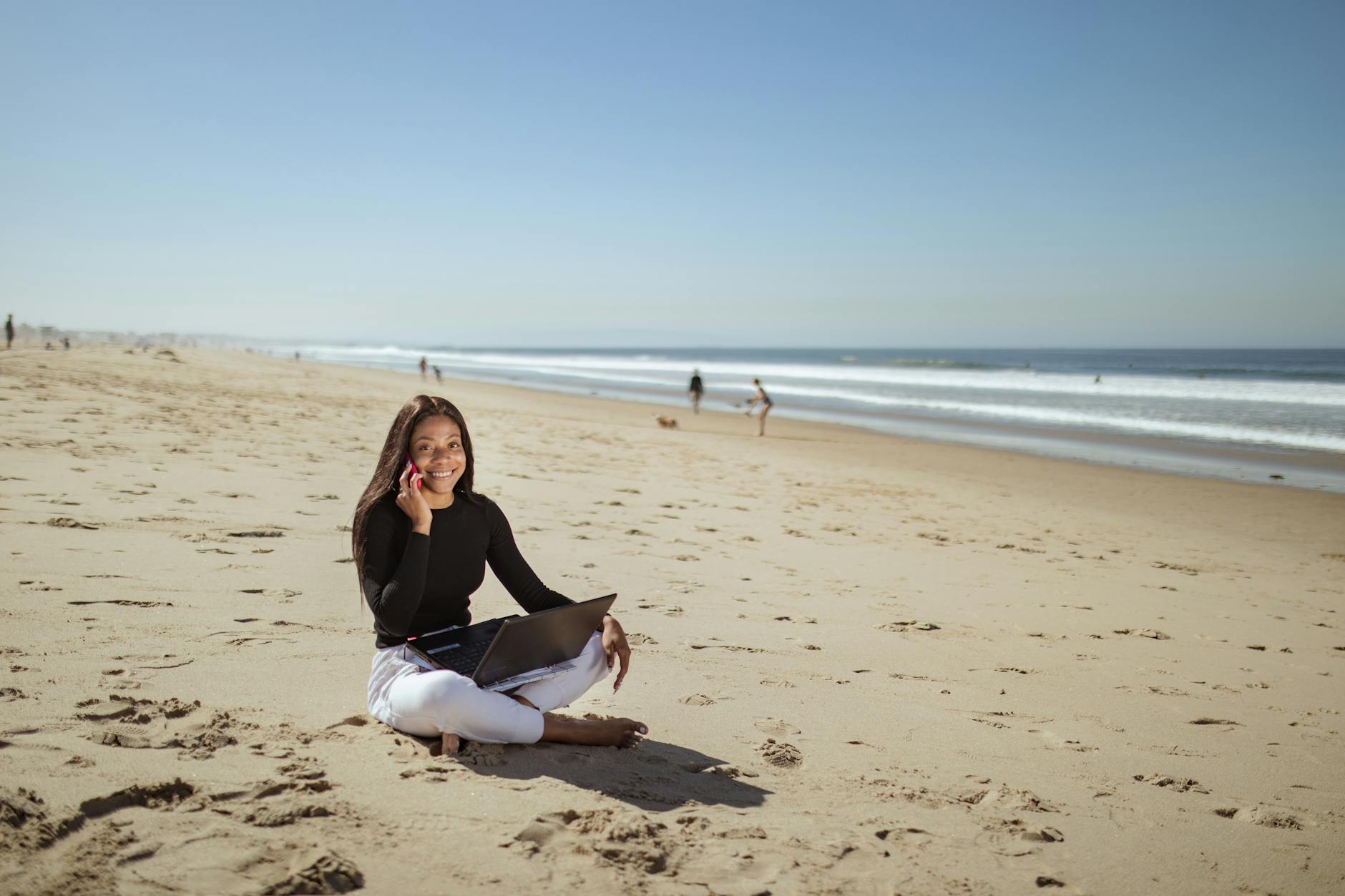 Person working remotely on laptop with tropical beach setting in background