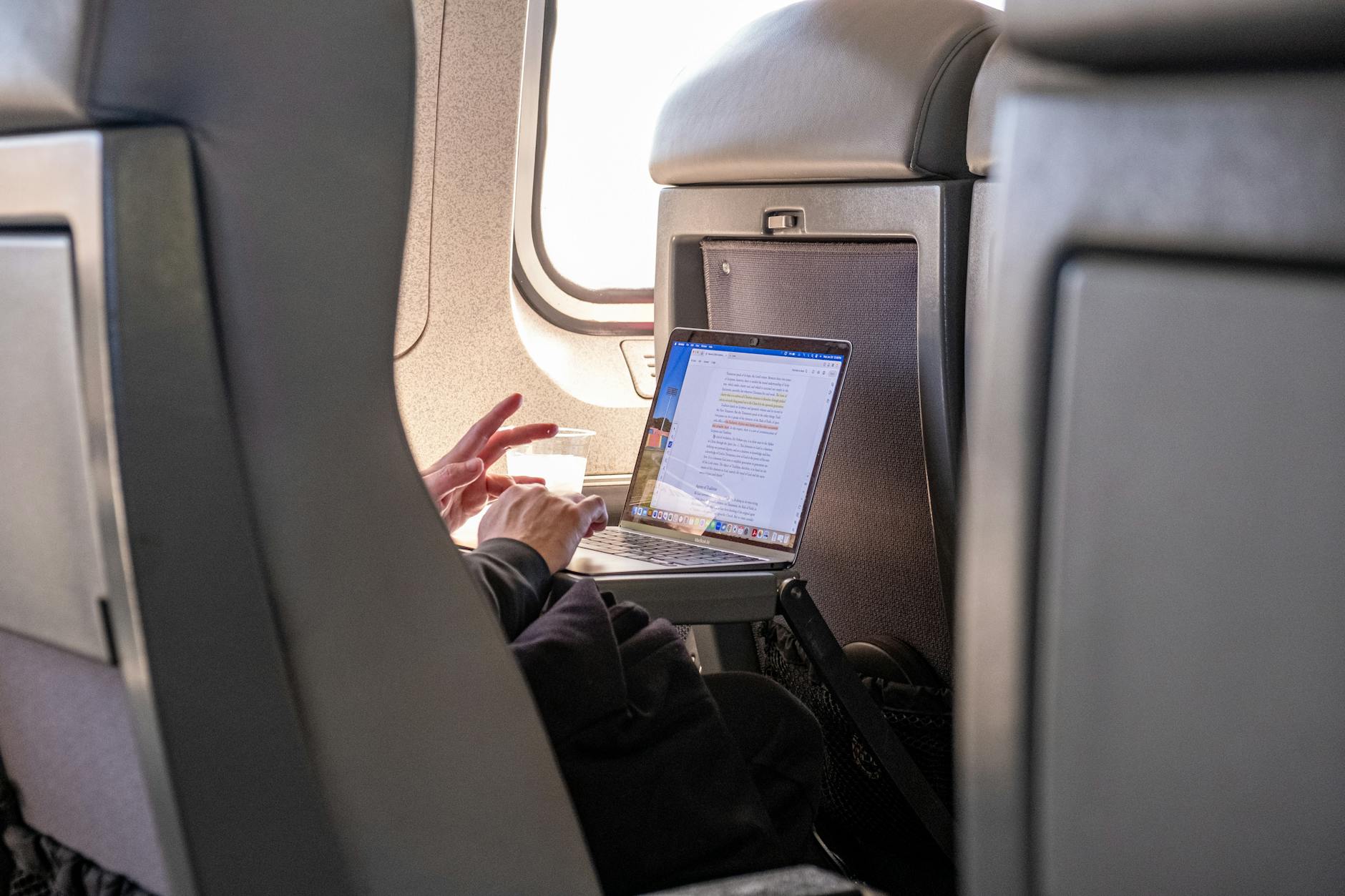 Business traveler using laptop computer on airplane with privacy screen