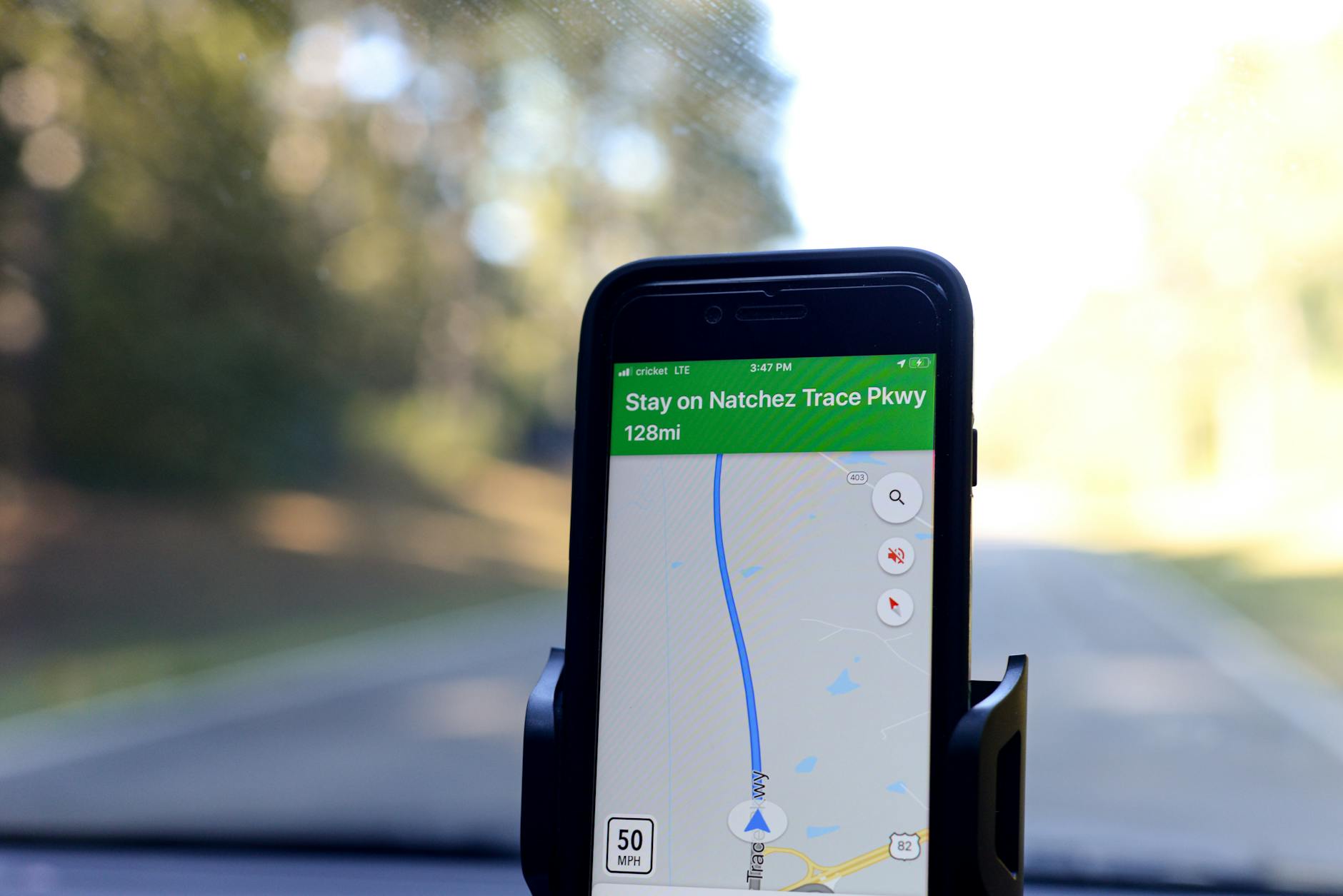 Hand holding smartphone displaying GPS map navigation interface