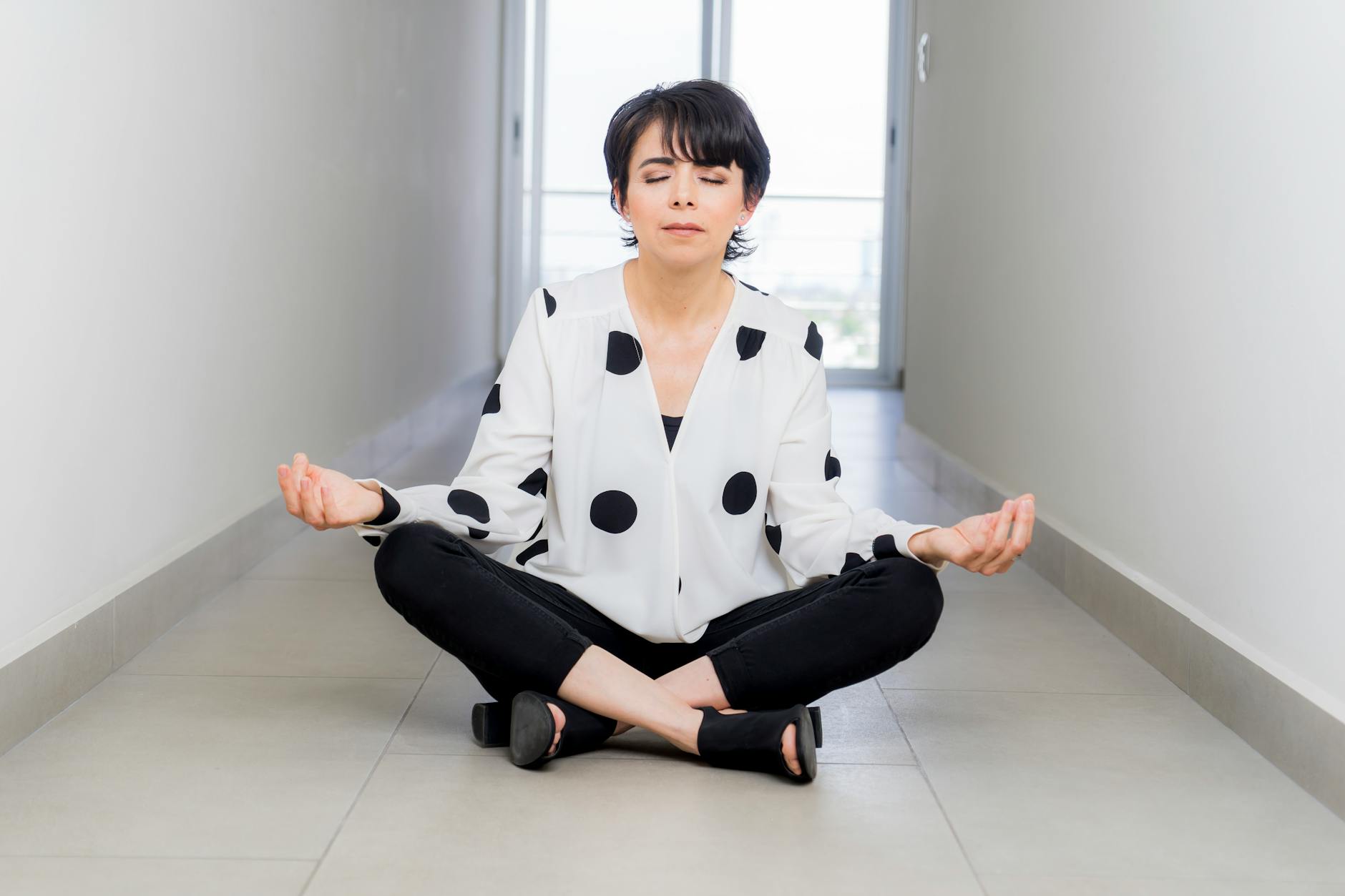 Professional businessperson in formal attire sitting in meditation pose in modern office