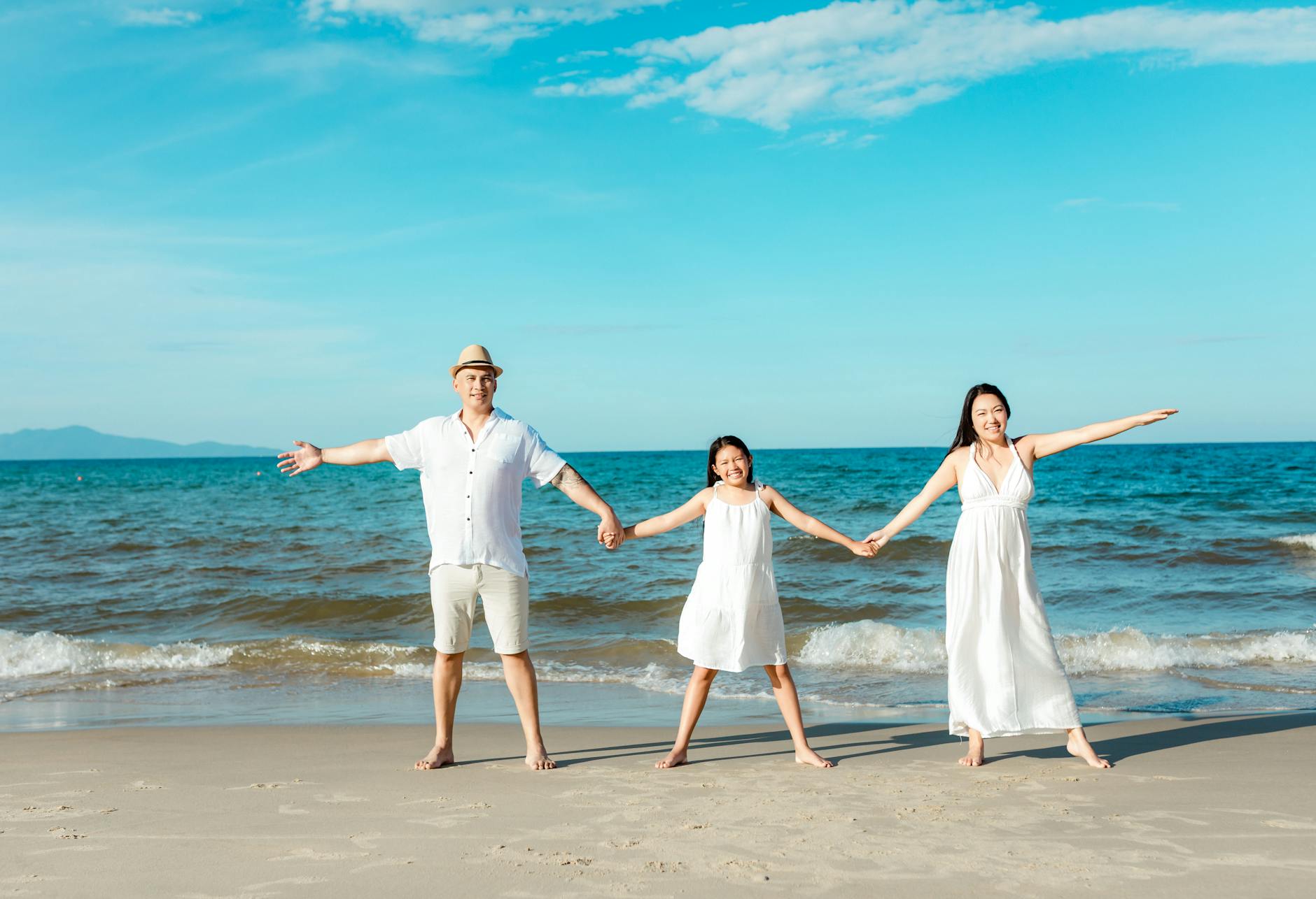 Happy family walking together on tropical beach during vacation