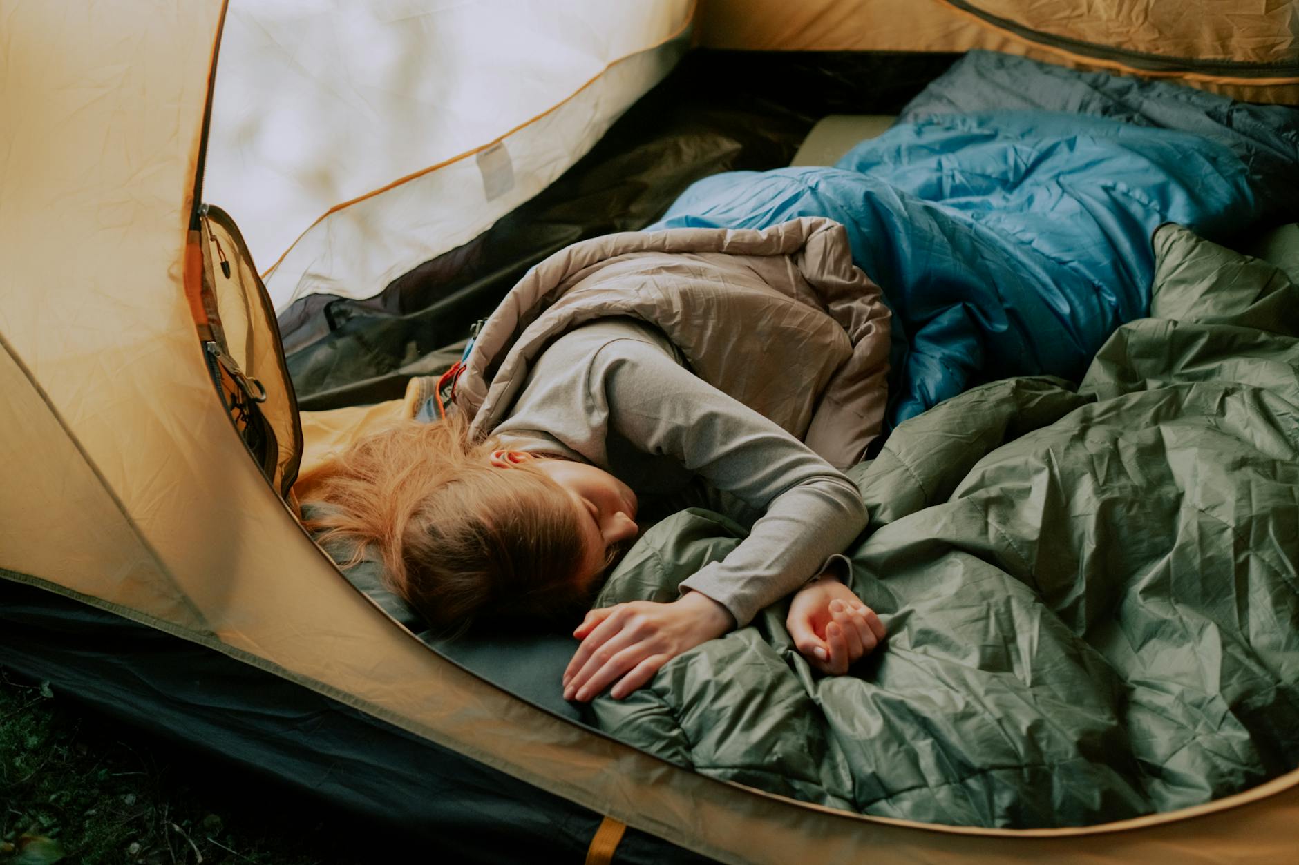 Person in sleeping bag lying on cave floor looking up at ceiling in darkness