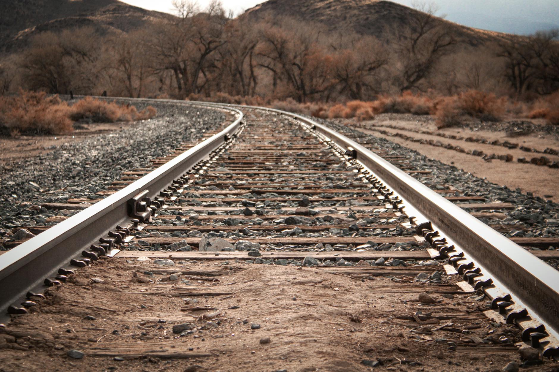 Railway tracks extending across open plains under dramatic African sky