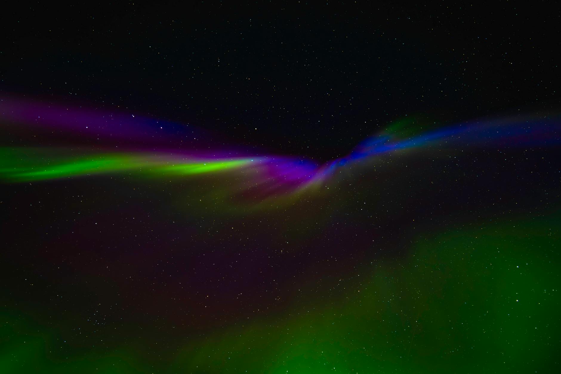 Brilliant green and purple aurora borealis dancing across dark Arctic night sky