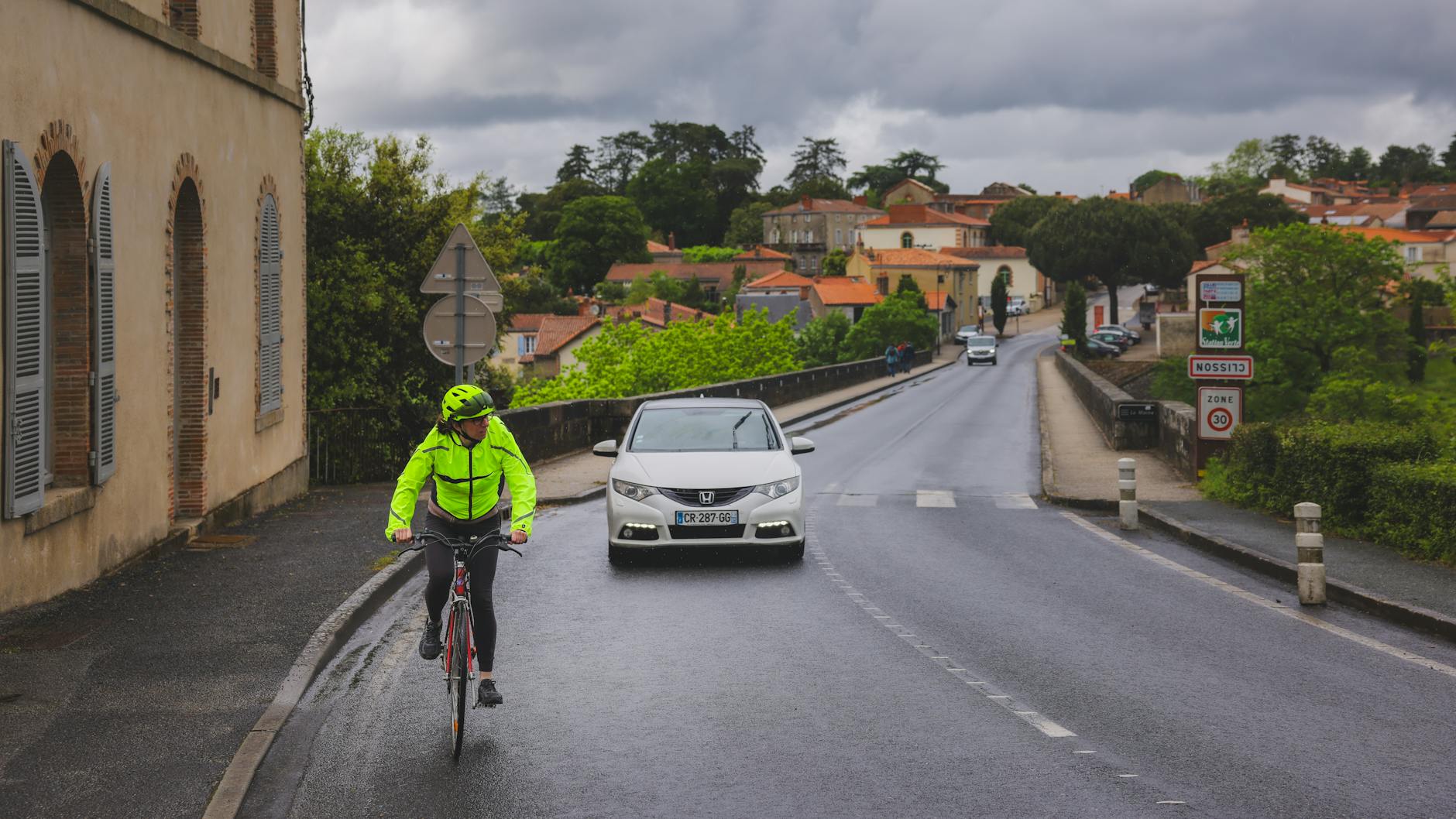 Cyclists riding through scenic European countryside with vineyards and rolling hills