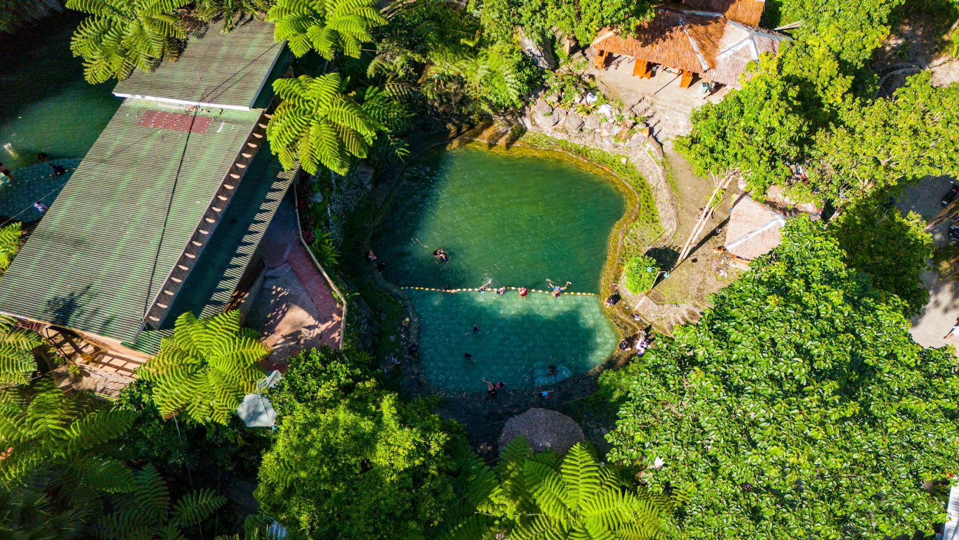 Natural swimming hole surrounded by lush jungle vegetation and limestone formations