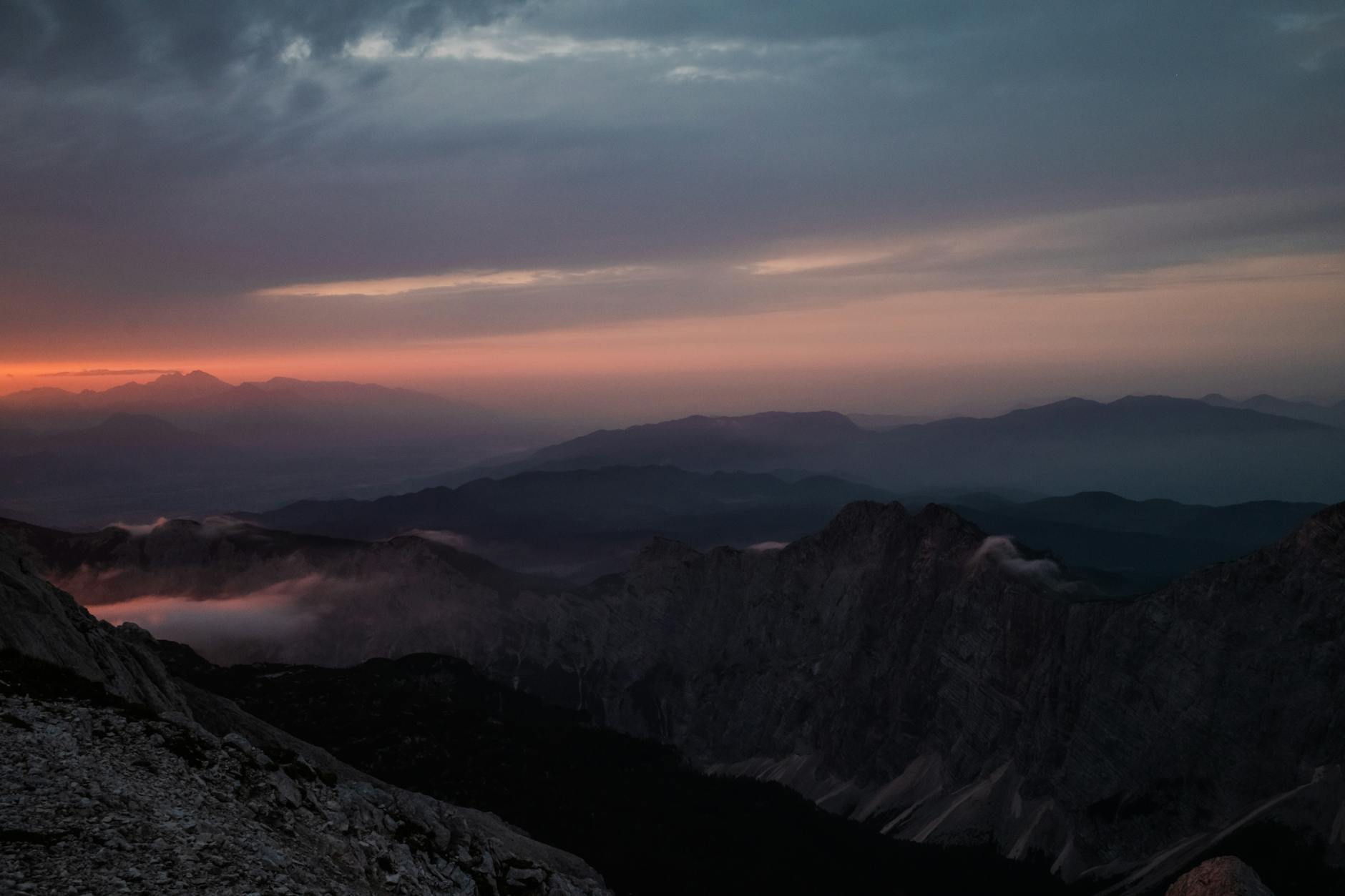 Mountain summit bathed in golden sunrise light with rocky terrain