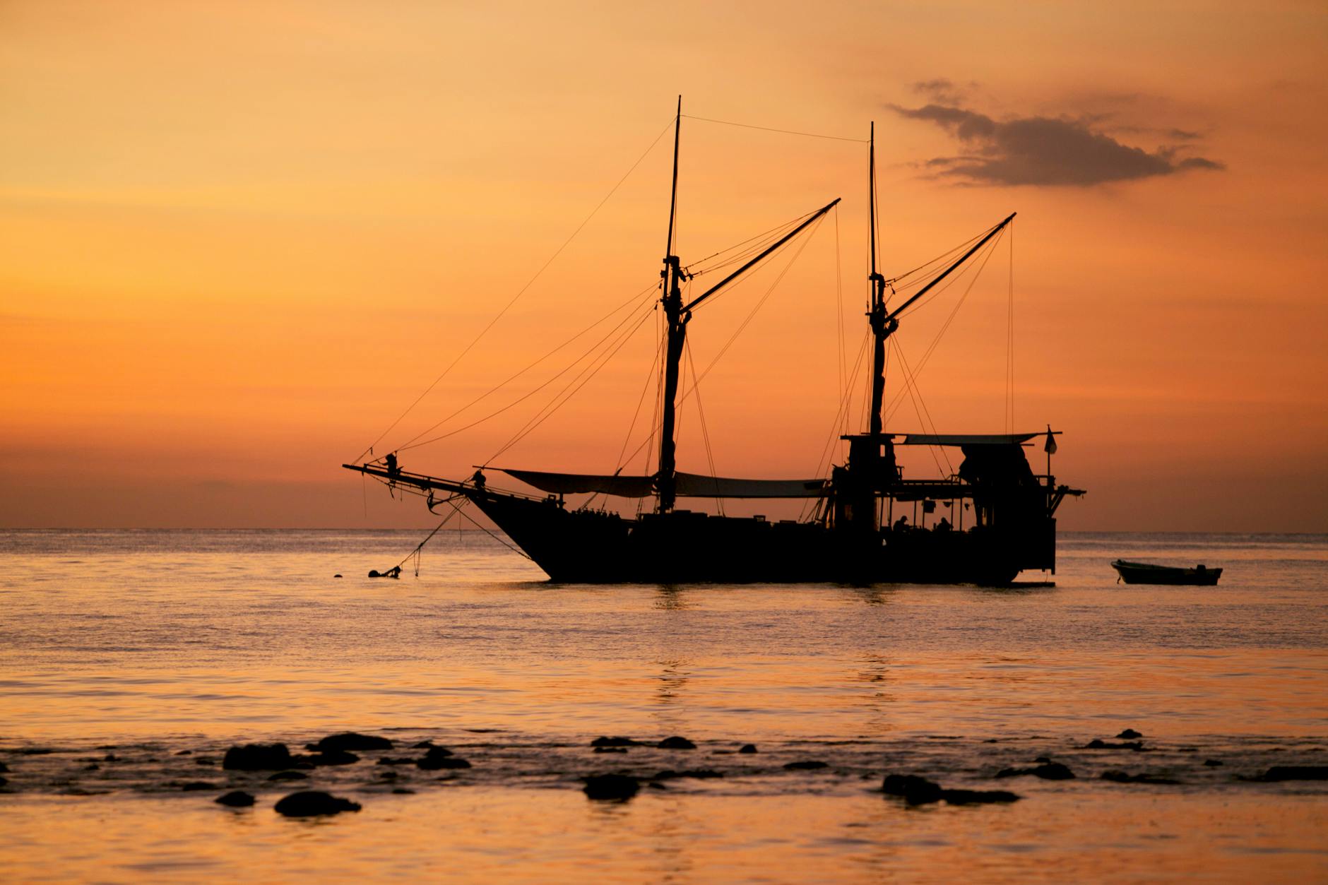 Silhouette of boat on calm ocean waters during golden hour sunset