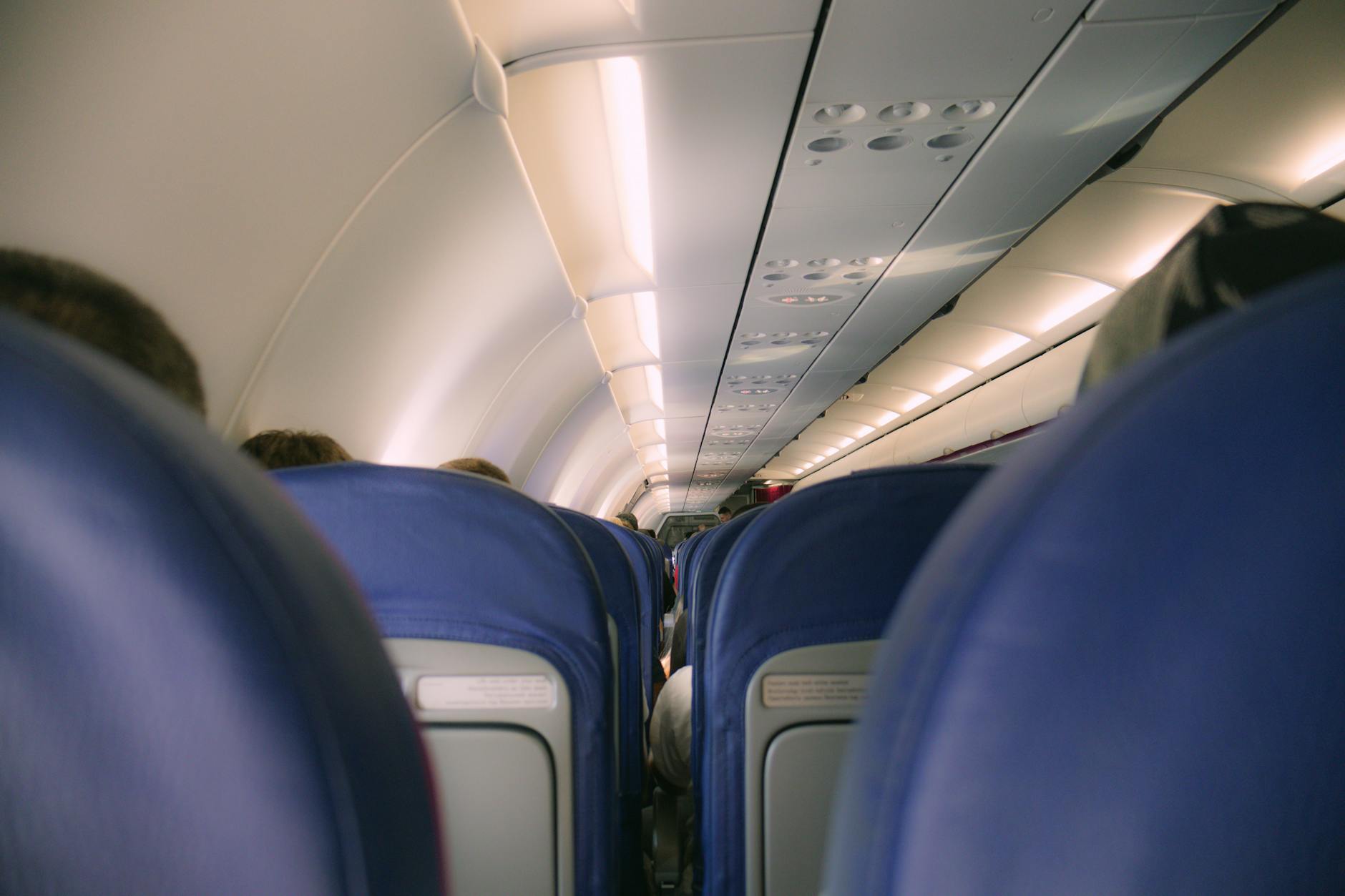 Diverse group of airline passengers boarding aircraft with carry-on luggage