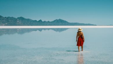 Vast salt flat surface covered in shallow water reflecting a colorful sunrise sky