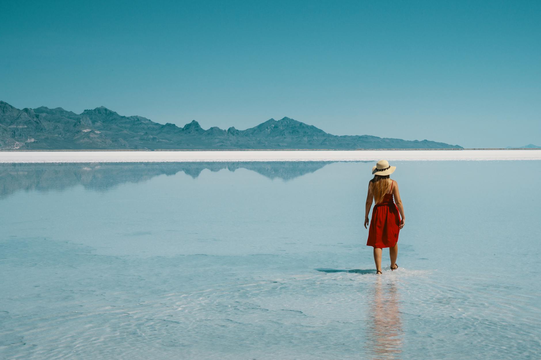 Vast salt flat surface covered in shallow water reflecting a colorful sunrise sky
