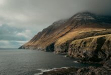 Dramatic green cliffs and ocean coastline of the Faroe Islands on a cloudy day