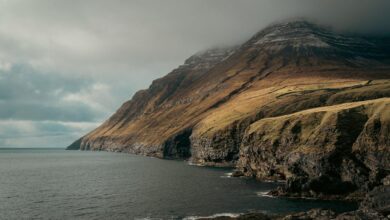 Dramatic green cliffs and ocean coastline of the Faroe Islands on a cloudy day