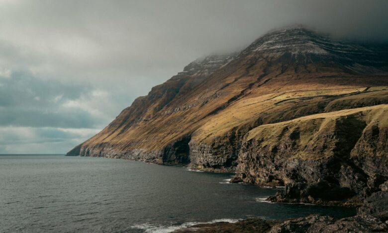 Dramatic green cliffs and ocean coastline of the Faroe Islands on a cloudy day