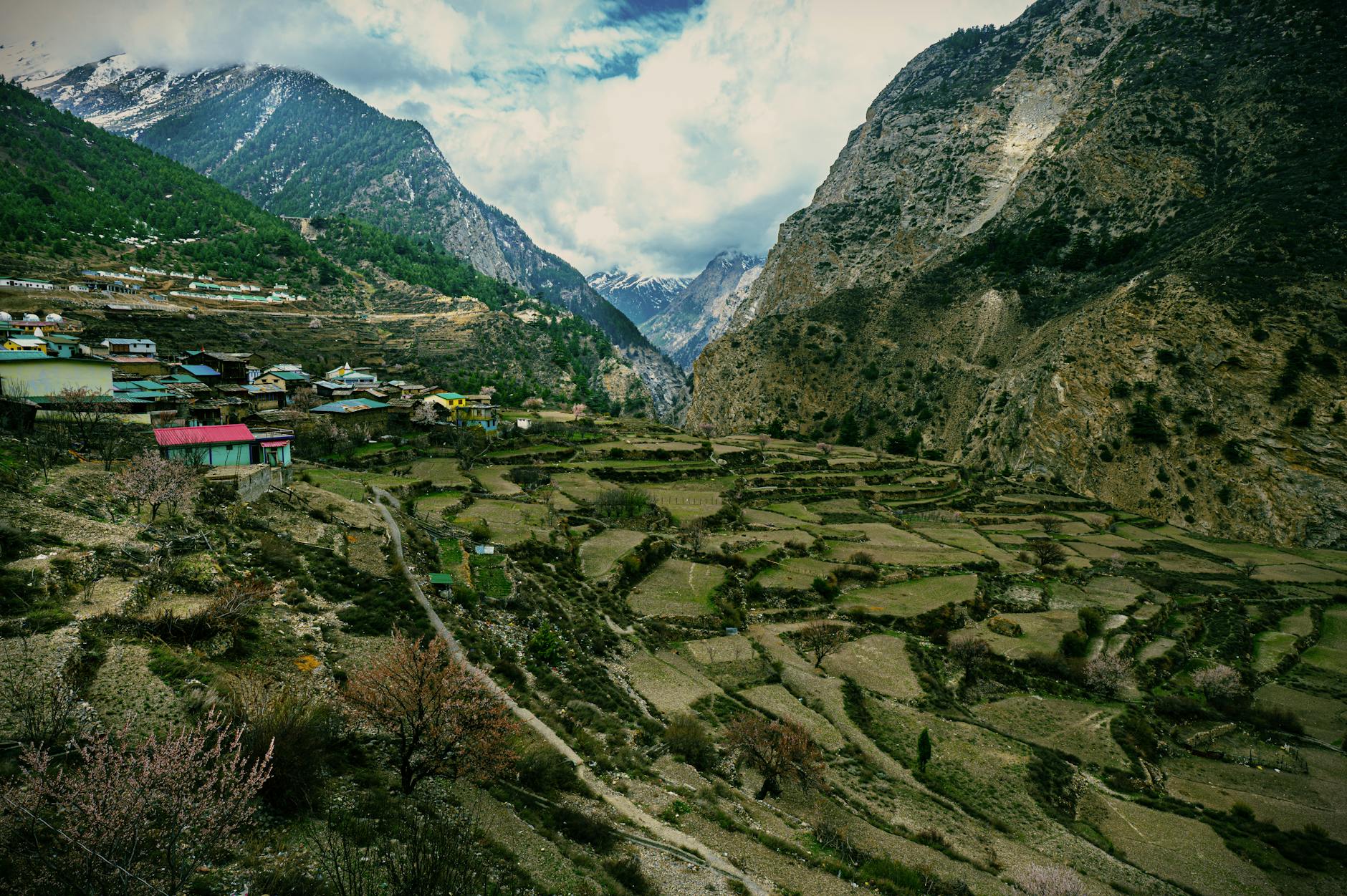 Remote Himalayan village with whitewashed buildings set against dramatic rocky cliffs in Upper Mustang, Nepal
