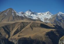 Snow-capped Caucasus mountain peaks rising above a green highland valley in Georgia