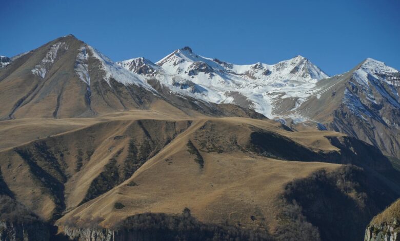 Snow-capped Caucasus mountain peaks rising above a green highland valley in Georgia