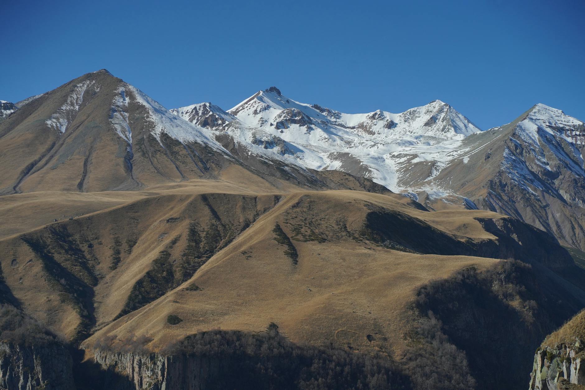 Snow-capped Caucasus mountain peaks rising above a green highland valley in Georgia