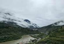 Scenic view of a lush Himalayan valley with traditional Bhutanese architecture surrounded by green hills