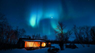 Glass dome cabin with aurora borealis visible in the night sky above