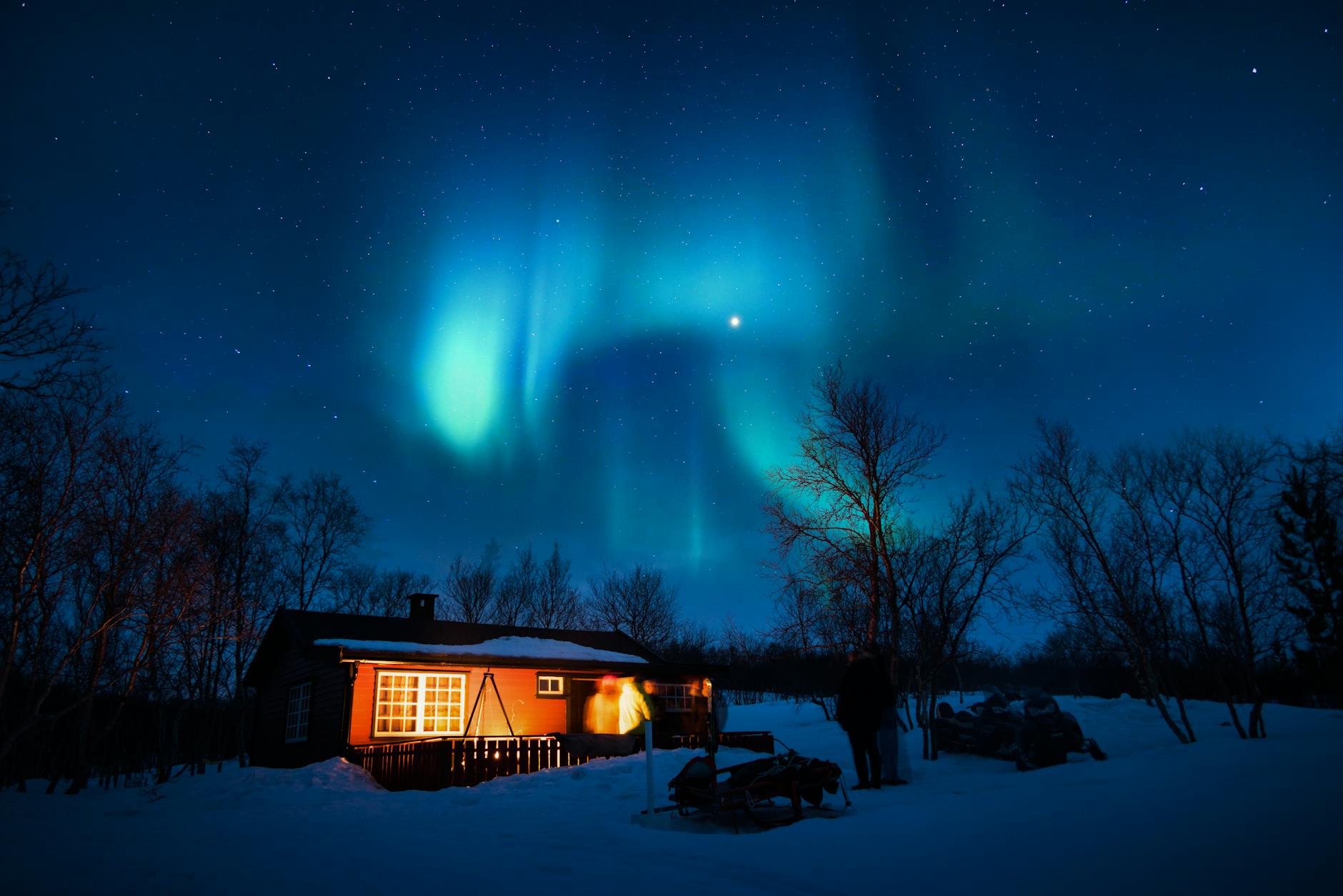 Glass dome cabin with aurora borealis visible in the night sky above